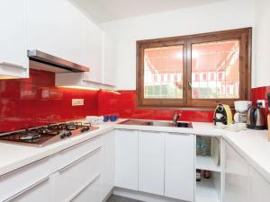 タマリウにあるVilla Chez Noux by Interhomeの白いキャビネットと赤い壁のキッチン