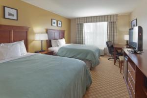 a hotel room with two beds and a desk and a television at Country Inn & Suites by Radisson, Holland, MI in Holland +32 photos