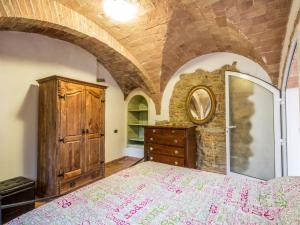 a bedroom with a large bed and a wooden dresser at Apartment La Fonte by Interhome in Volterra