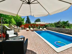 a swimming pool with an umbrella and chairs and a swimming pool at Apartment Lidija by Interhome in Matulji