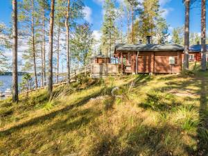 uma cabana na floresta ao lado de um corpo de água em Holiday Home Kannonniemi by Interhome em Majavesi