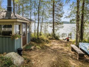 un bâtiment avec un banc à côté d'une masse d'eau dans l'établissement Holiday Home Huotarin mökki by Interhome, à Tervajärvi