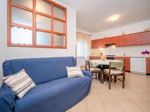 a living room with a blue couch and a kitchen at Apartment Adriana by Interhome in Pješčana Uvala 