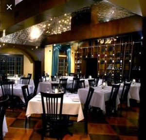 a dining room with white tables and black chairs at 1-Bedroom Cozy Sweet #22 by Amazing Property Rentals in Gatineau