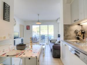 a kitchen and living room with a table and a couch at Apartment Royal Rivage-2 by Interhome in Carqueiranne