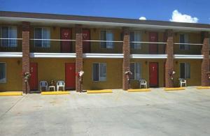 un grande edificio con porte e sedie rosse in un parcheggio di Color Country Motel a Panguitch