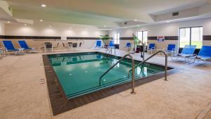 a large swimming pool with blue chairs and tables at Best Western Plus Ardmore Inn & Suites in Ardmore