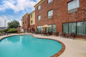 a swimming pool in front of a brick building at Comfort Suites Ennis in Ennis