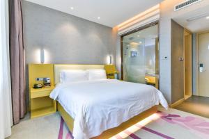 ein Schlafzimmer mit einem großen weißen Bett und einer ebenerdigen Dusche in der Unterkunft Lavande Hotel Shanghai Jiading Xincheng Stadium Branch in Jiading