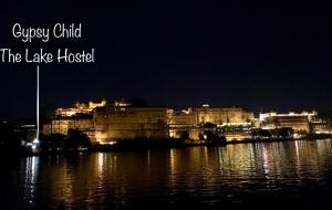 a city at night with a large body of water at Gypsy Child Lake Hostel Udaipur in Udaipur