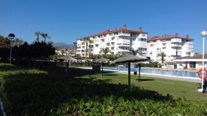 a resort with a pool with umbrellas and a building at Apartamentos Laguna Beach in Torrox Costa