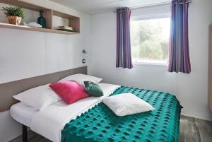 a bed with colorful pillows on it in a room at Camping Porte des Vosges in Bulgnéville