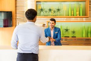 a man shaking another mans hand at a counter at ibis Deira Creekside Dubai in Dubai