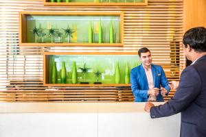 two men shaking hands at a table with a display of green vases at ibis Deira Creekside Dubai in Dubai