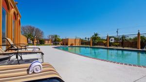 uma piscina com um banco ao lado de um edifício em Best Western Northwest Corpus Christi Inn & Suites em Corpus Christi