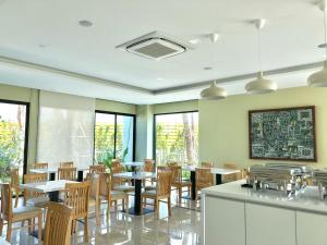 una sala da pranzo con tavoli, sedie e finestre di Porestva Hotel Sriracha a Si Racha