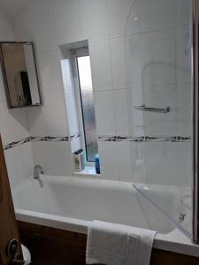 a bathroom with a tub and a shower with a mirror at Avon House in Telford