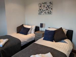 a bedroom with two beds with blue pillows at Avon House in Telford