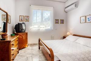 a bedroom with a bed and a tv and a window at A gem next to the sea and close to the airport in Dhaskalión