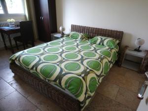 a bedroom with a bed with a green and white comforter at Les Hauts de Cavanello in Zonza