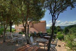 een patio met een tafel en stoelen en een tafel en bomen bij Les Hauts de Cavanello in Zonza