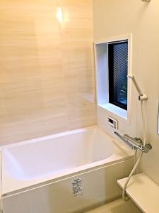 une baignoire blanche dans une salle de bains avec fenêtre dans l'établissement Nice Kyoto, à Kyoto 15 autres photos