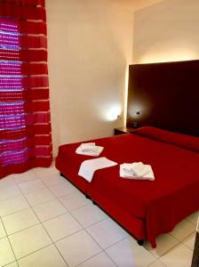 una camera da letto con un letto rosso e asciugamani di Residence Domus a Rimini