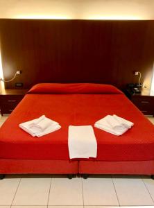 un letto rosso con due asciugamani bianchi sopra di Residence Domus a Rimini