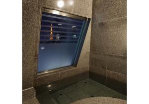 a shower with a view of the eiffel tower through a window at Hotel Check In Shimbashi in Tokyo