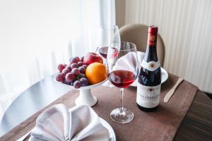a table with a bottle of wine and a bowl of fruit at Hotel Home Parq in Ekibastuz