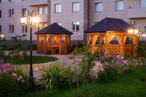 two gazebos in a garden in front of a building at Hotel Home Parq in Ekibastuz