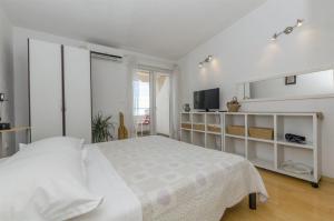 a white bedroom with a bed and a television at Apartments Zanet in Sumpetar