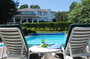 un tavolo con un bicchiere di vino e due sedie accanto a una piscina di Hôtel au Petit Berger a La Malbaie