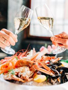 two people are holding wine glasses over a plate of seafood at Opus 16 in Bergen