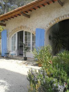 a house with blue doors and a chair on a porch at la Cigalette in Peypin