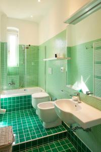 a green tiled bathroom with two sinks and a tub at CASACUADRA San Giusto in Trieste