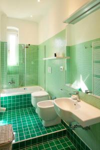Un baño de azulejos verdes con dos lavabos y una bañera. en CASACUADRA San Giusto, en Trieste