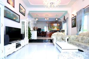 ein Wohnzimmer mit einem Sofa und einem TV in der Unterkunft Palm Villa 19 in Vũng Tàu