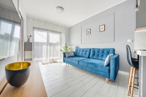 un sofá azul en una sala de estar blanca en Apartamenty Sun & Snow Gardenia en Dziwnów