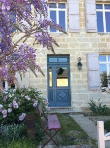 a blue door on a stone house with purple flowers at Les chambres du Font d'Uzas in Meilhan-sur-Garonne