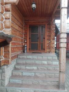 une porte d'entrée d'une cabane en rondins avec des escaliers. dans l'établissement На Беріжку, à Mykulychyn