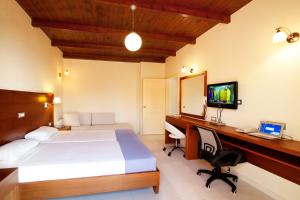 a bedroom with a bed and a desk with a computer at Giorgi's Blue Apartments in Kalathas