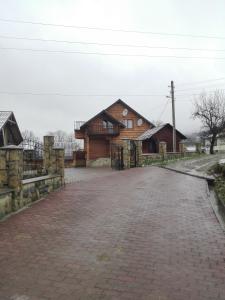 una strada di mattoni di fronte a una casa di legno di На Беріжку a Mykulychyn