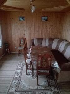 a dining room with a table and chairs and a couch at На Беріжку in Mykulychyn