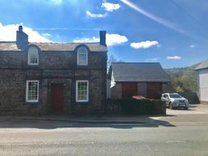 uma casa de tijolos com um carro estacionado em frente em Post Office Row Apartment and garden em Crickhowell