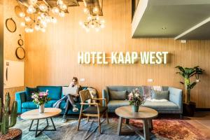 Una mujer sentada en un sofá en un hotel en el vestíbulo oeste en Hotel Kaap West I Kloeg Collection en Westkapelle