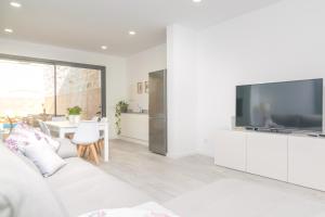 a white living room with a large flat screen tv at Can Serra in Sa Pobla