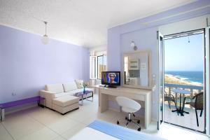 a living room with a couch and a desk with a television at Giorgi's Blue Apartments in Kalathas