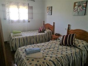 a bedroom with two beds and a window at Casa el Pino in Cortes de la Frontera