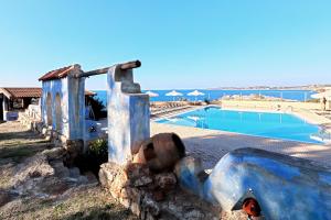 a swimming pool next to a stone wall next to the ocean at Giorgi's Blue Apartments in Kalathas
